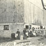 孩子们排成一行 沿谷仓墙外举着牛奶桶