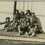 一群儿童坐在楼外草坪上