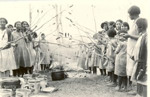 孩子们站在火堆旁用棍子握起wieners